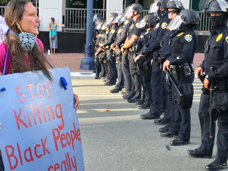 A protester holds a sign that reads "stop killing black people" in front of the police line during a protest in Downtown San Diego.
