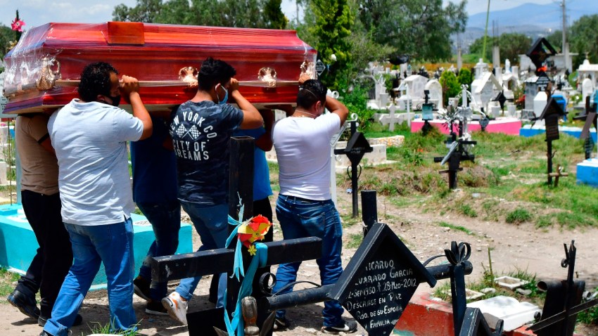 Hombres cargan un féretro en un cementerio.