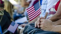 Hand holding a small American flag during a patriotic presentation for Veteran's Day.