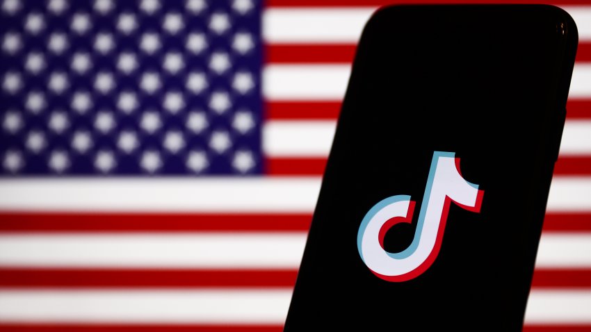 TikTok logo displayed on a phone screen and American flag displayed on a screen in the background are seen in this illustration photo taken in Krakow, Poland on January 30, 2023. (Photo by Jakub Porzycki/NurPhoto via Getty Images)