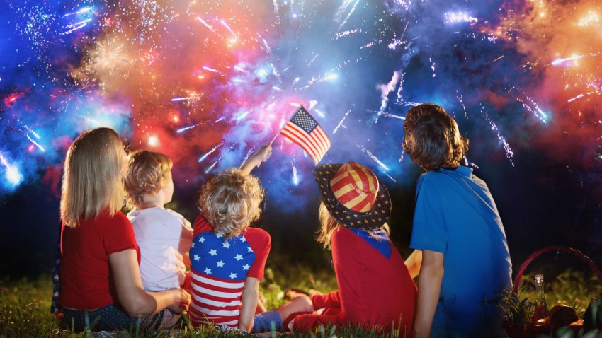 American family celebrating Independence Day. Picnic and fireworks on 4th of July in America. USA flag. Parents and kids celebrate US holiday. Children watching firework.