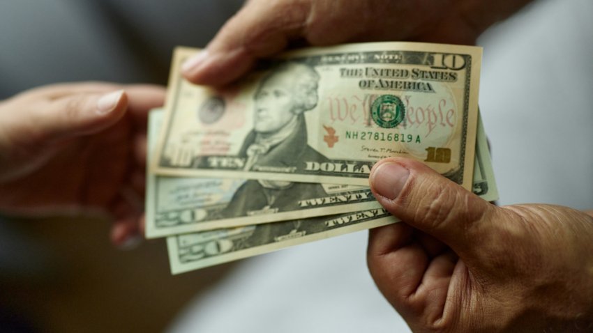 Close up of unrecognizable man paying someone with dollars.