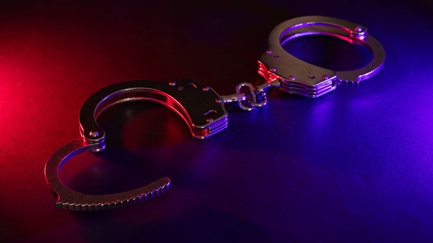 Closed handcuffs on the street pavement at night with police car lights high contrast image.