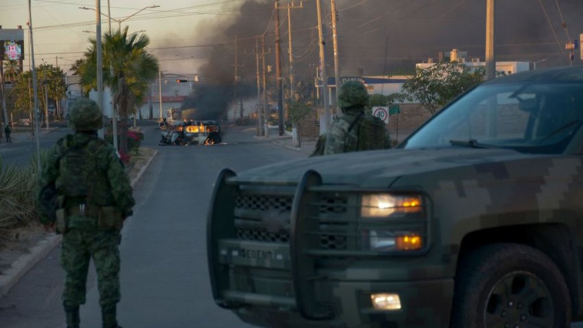 TOPSHOT – Mexicans soldiers stand guard near burning vehicles on a street during an operation to arrest the son of Joaquin “El Chapo” Guzman, Ovidio Guzman, in Culiacan, Sinaloa state, Mexico, on January 5, 2023. – Mexican security forces on Thursday captured a son of jailed drug kingpin Joaquin “El Chapo” Guzman, scoring a high-profile win in the fight against powerful cartels days before US President Joe Biden visits. Ovidio Guzman, who was arrested in the northwestern city of Culiacan, is accused of leading a faction of his father’s notorious Sinaloa cartel, Defense Minister Luis Cresencio Sandoval told reporters. (Photo by Juan Carlos CRUZ / AFP) (Photo by JUAN CARLOS CRUZ/AFP via Getty Images)