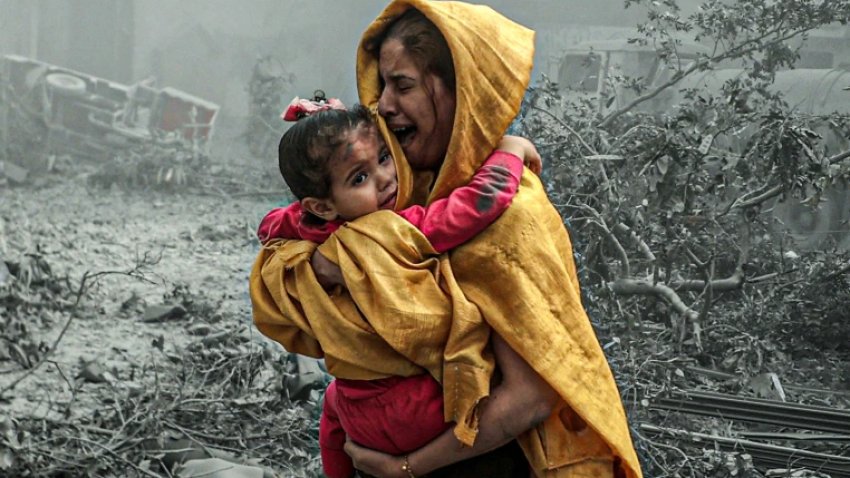 A woman cries holding a child after Israeli airstrikes in Gaza City last October