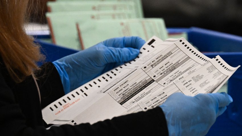 An election worker unfolds a voted ballot inside the Maricopa County Tabulation and Election Center (MCTEC) on Election Day, November 5, 2024 in Phoenix, Arizona. Pairs of election workers from different political parties open mail-in ballot envelopes containing voted ballots after they completed signature verification. (Photo by Patrick T. Fallon / AFP) (Photo by PATRICK T. FALLON/AFP via Getty Images)