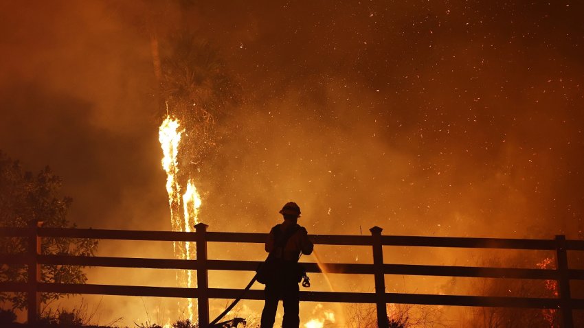 MALIBU, CALIFORNIA – DECEMBER 10: A firefighter sprays water as the Franklin Fire burns palm trees on December 10, 2024 in Malibu, California. The wildfire has scorched 1,800 acres near Pepperdine University prompting evacuations along the coast amid high winds with some structures destroyed. (Photo by Mario Tama/Getty Images)