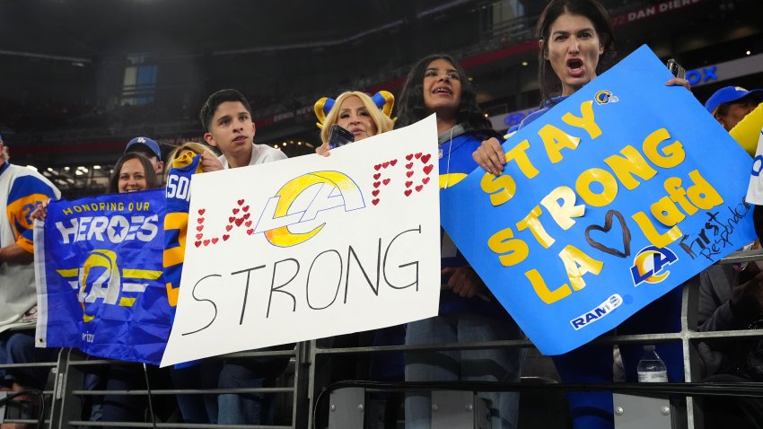 Aficionados de los Rams de Los Ángeles sostienen pancartas en apoyo a la ciudad de Los Ángeles por los incendios forestales antes del encuentro del comodín ante los Vikings de Minnesota el lunes 13 de enero del 2025 en Glendale, Arizona. (AP Foto/Ross D. Franklin)