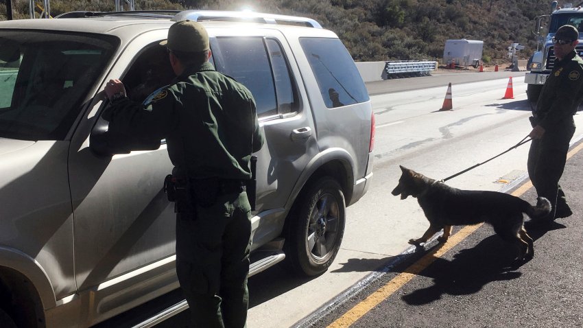 ARCHIVO – Agentes de la Patrulla Fronteriza se apoyan en un elemento canino en la revisión vehicular en un punto de revisión de Pine Valley, California, en la principal vía de Arizona a San Diego, el 14 de diciembre de 2017 (AP Foto/Elliot Spagat, archivo)